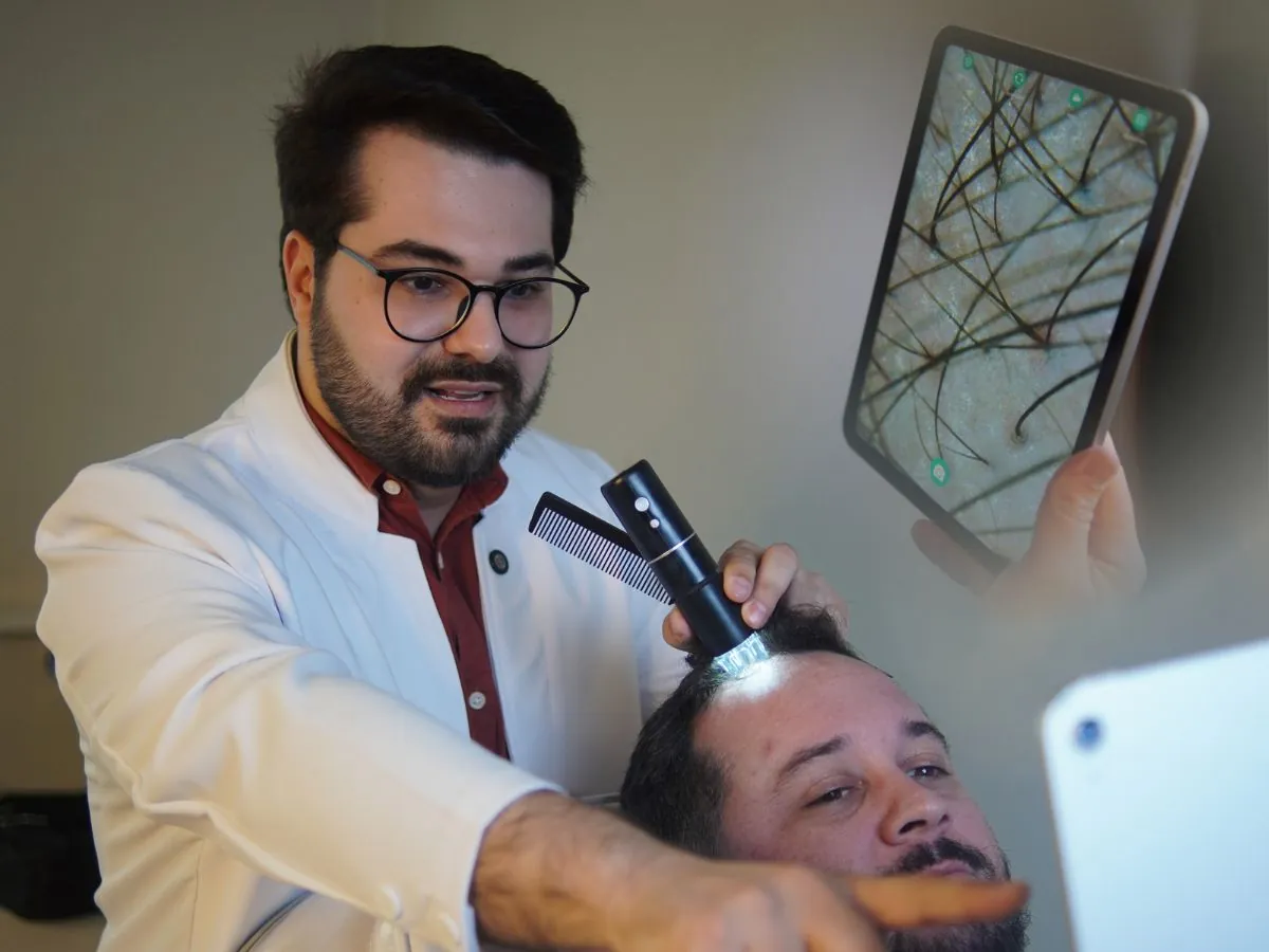 Dr. Éric Aguiar realizando tricoscopia digital no couro cabeludo de um paciente