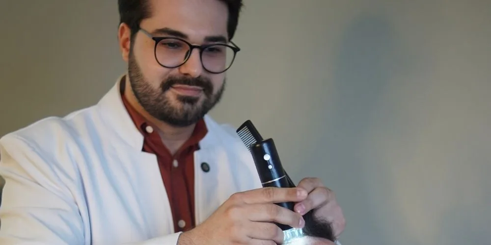 Dr. Éric Aguiar realizando tricoscopia do couro cabeludo durante a consulta médica